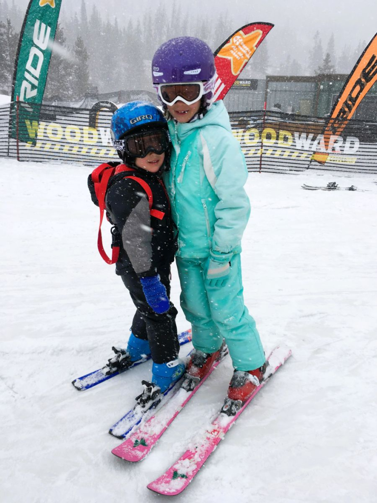 boy and girl skiers posing in front of ski school