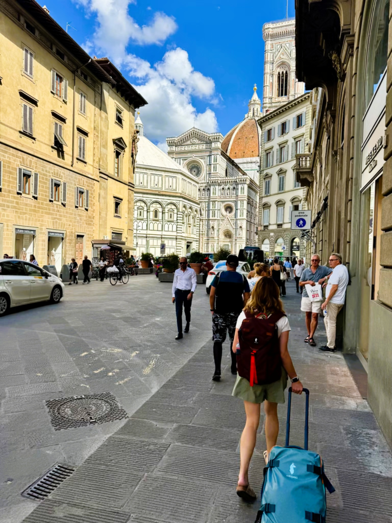 back of woman walking through rome with luggage